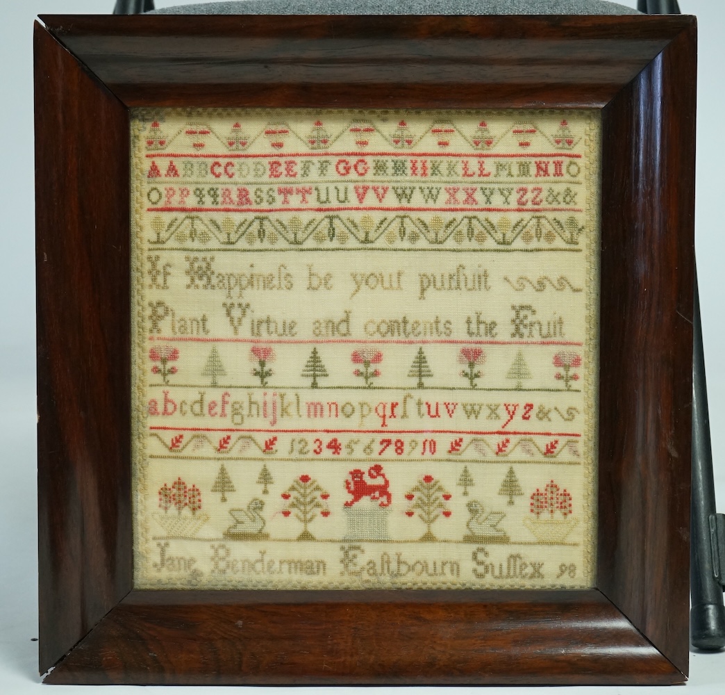 A 19th century sampler by Jane Benderman, Eastbourn, Sussex, 98. Worked in reds and greens on a yellow background, in rows of alphabet, numerals and spot motifs of swans, flowers, trees with a central lion motif, in a ro